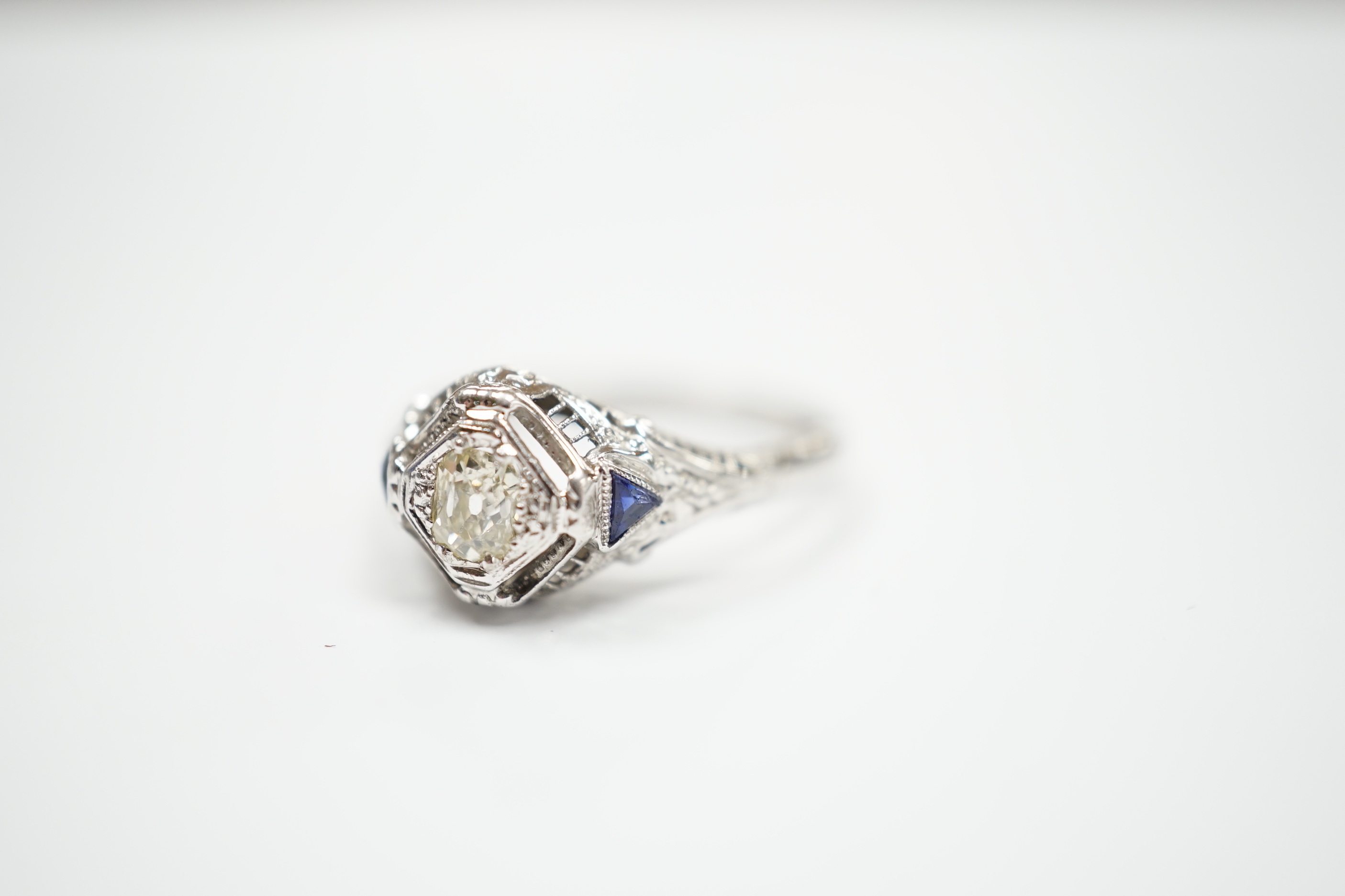 An 18ct and single stone diamond set ring, with two stone triangular sapphire set shoulders, size P, gross weight 3.1 grams.